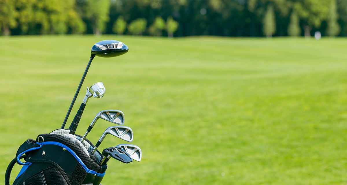 photo of golf clubs in bag with green in the background