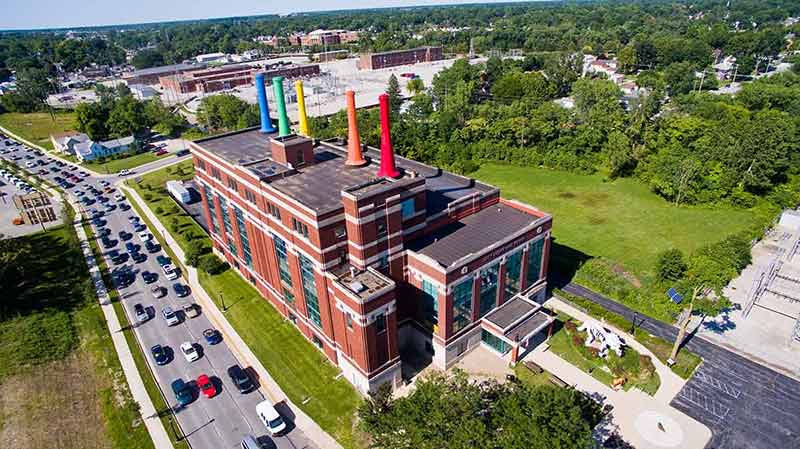 things to do in fort wayne in Image of Aerial shot of a brick building with multicolored chimneys Science Central in Fort Wayne Indiana surrounded by trees.