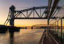 20 Things To Do In Hannibal, Missouri That Channel Mark Twain Vibes sunset as a cruise ship floats beneath the mark twain memorial bridge