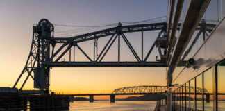 sunset as a cruise ship floats beneath the mark twain memorial bridge