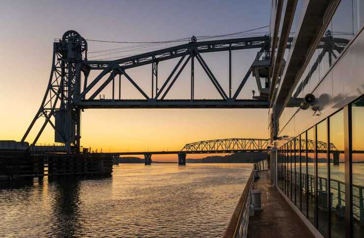 20 Things To Do In Hannibal, Missouri That Channel Mark Twain Vibes sunset as a cruise ship floats beneath the mark twain memorial bridge
