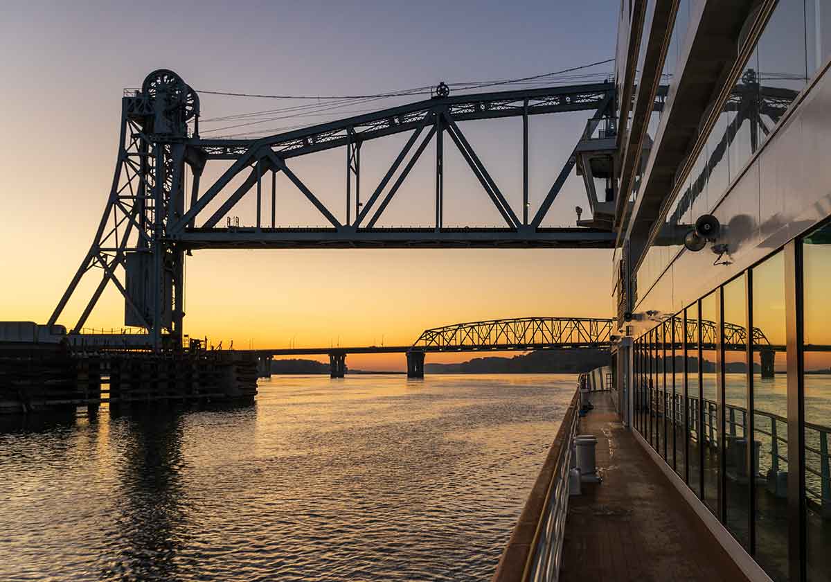 sunset as a cruise ship floats beneath the mark twain memorial bridge