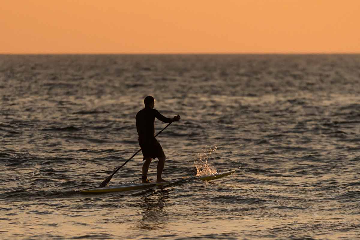 Man Paddleboarding at sunset