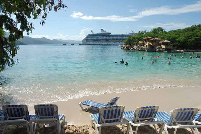 Beach loungers on the beach with cruise ship in the distance