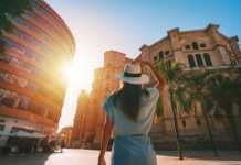things to do in malaga Rear view of young tourist woman in white sun hat walking in Malaga city at sunset.