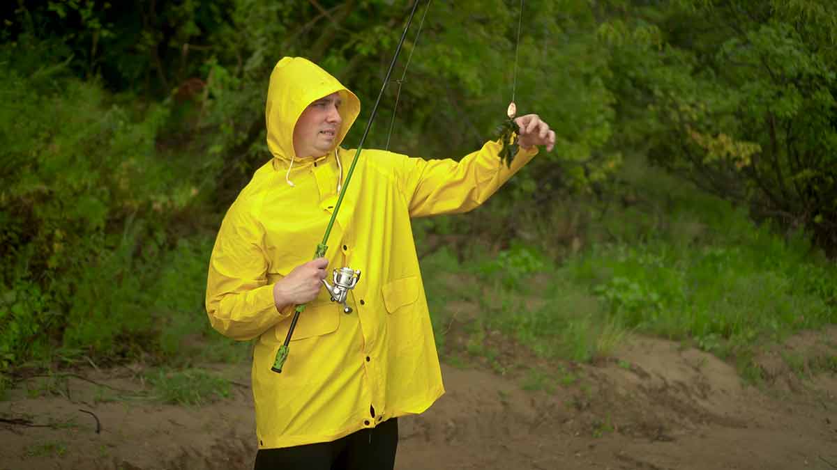 A Young Man In A Yellow Cloak With A Hood Is Fishing
