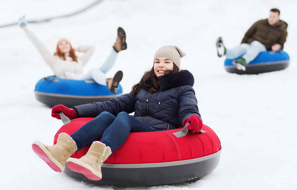 Group Of Happy Friends Sliding Down On Snow Tubes