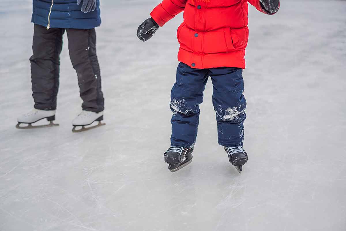Young Mother Teaching Her Little Son Ice Skating