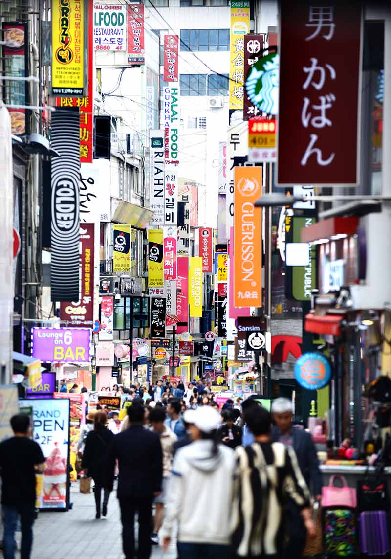 crowds walking beneath the colourful street signs in myeondong