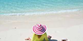 woman with a pink candy striped hat sitting on the sand in the Bahamas