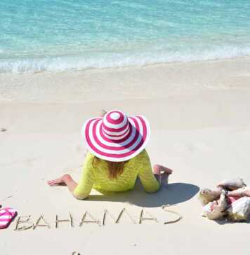 woman with a pink candy striped hat sitting on the sand in the Bahamas