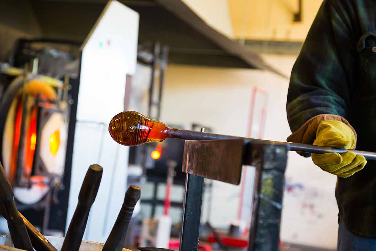 things to do in tulsa ok glassblower is forming and shaping glass in a studio for glass making.
