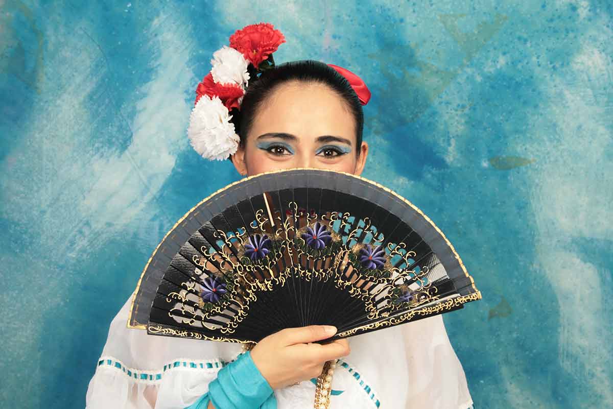 things to do in veracruz local with fan covering her face and flowers in her hair