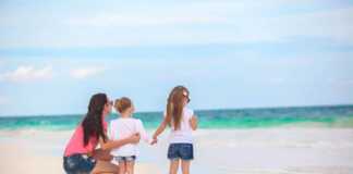 things to do with kids in cancun Rear view of fashion young mother and two her kids at exotic beach on sunny day