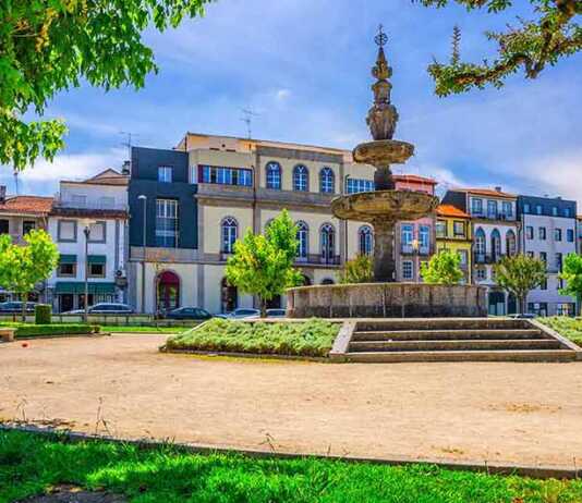 Fountain In Small Park And Typical Colorful Buildings Houses