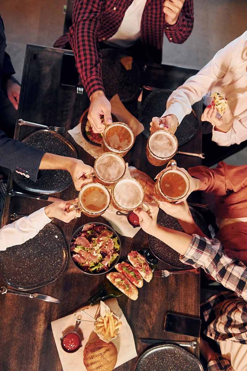 Group Of Young Friends Sitting Together In Bar With Beer