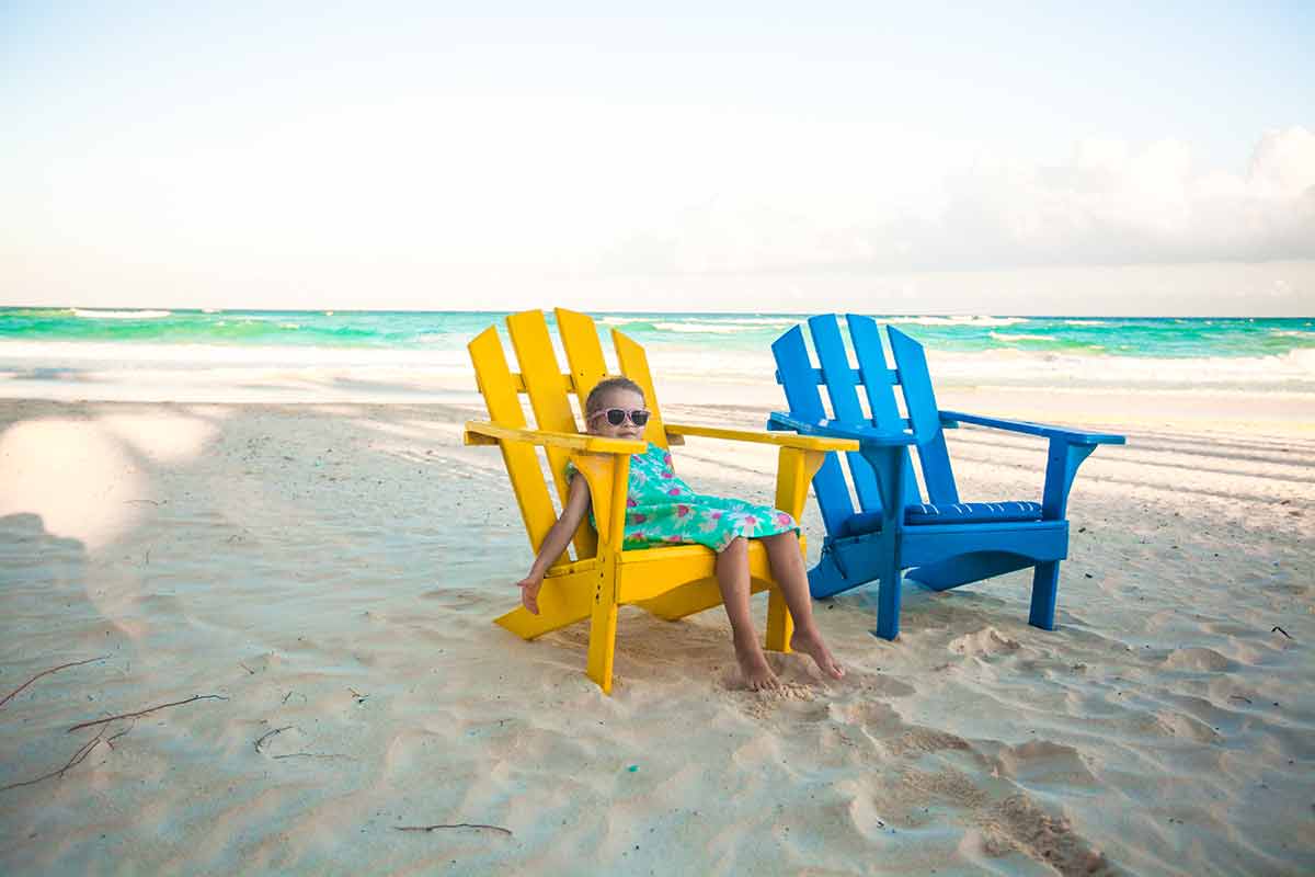 Little girl in beach wooden colorful chairs