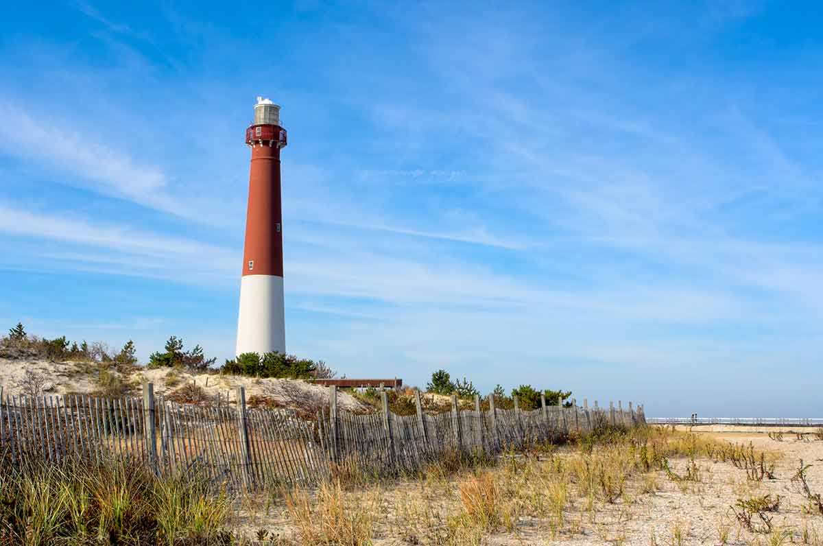 top beaches in new jersey A lighthouse on the beach. There is also an old wooden fence on the beach in this landscape.