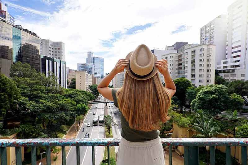 Back View Of Girl Holding Hat Enjoying View Of Sao Paulo Cityscape, Brazil.