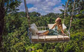 Young Woman Swinging In The Jungle Rainforest Of Bali Island