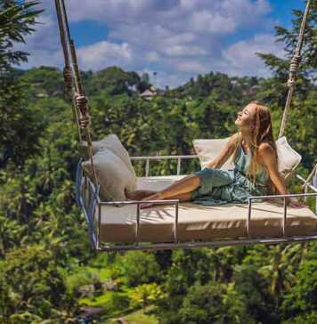Young Woman Swinging In The Jungle Rainforest Of Bali Island