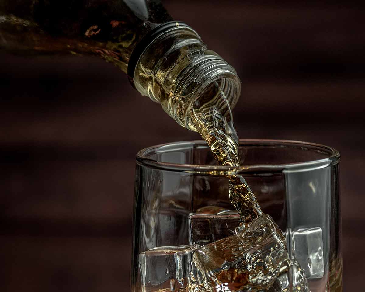 Whiskey Pours From A Bottle Into A Glass