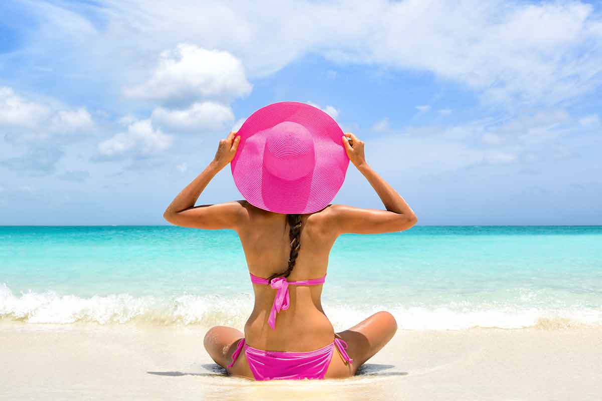 trinidad beaches tobago beaches woman in pink hat and pink bikini back view on a Caribbean beach