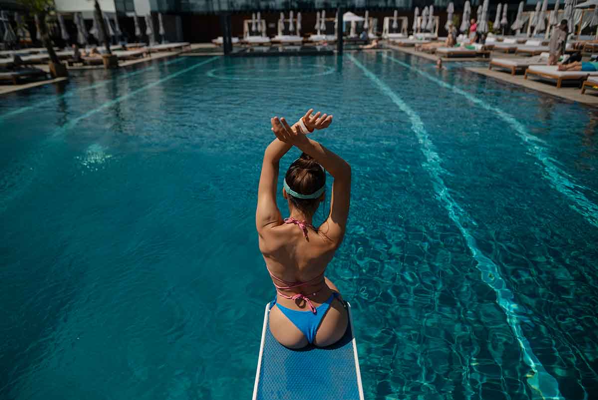 woman sitting on a diving board at the edge of a beach club pool