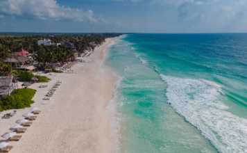 tulum hotels on beach aerial view of beach loungest, white sand and aquamarine water with waves lapping on shore