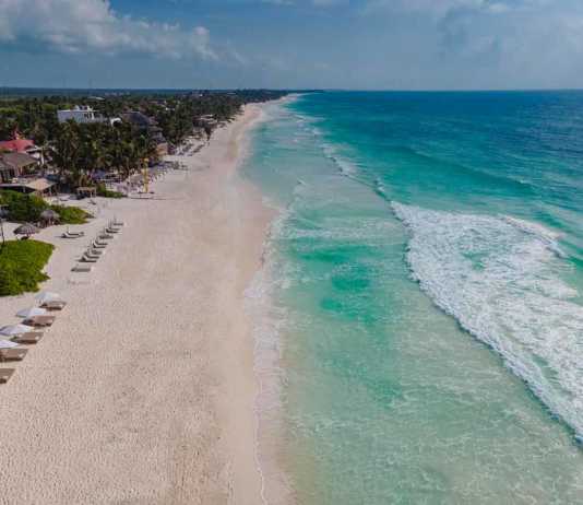 tulum hotels on beach aerial view of beach loungest, white sand and aquamarine water with waves lapping on shore