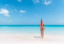 beautiful woman in red bikini wearing a snorkel walking out of the blue ocean in turks caicos