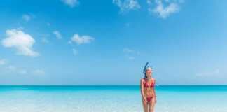 beautiful woman in red bikini wearing a snorkel walking out of the blue ocean in turks caicos