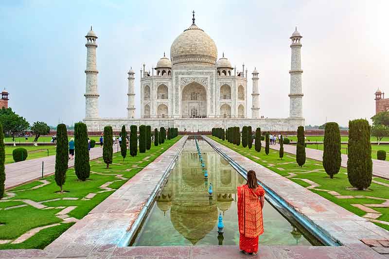 A woman standing front of Taj Mahal