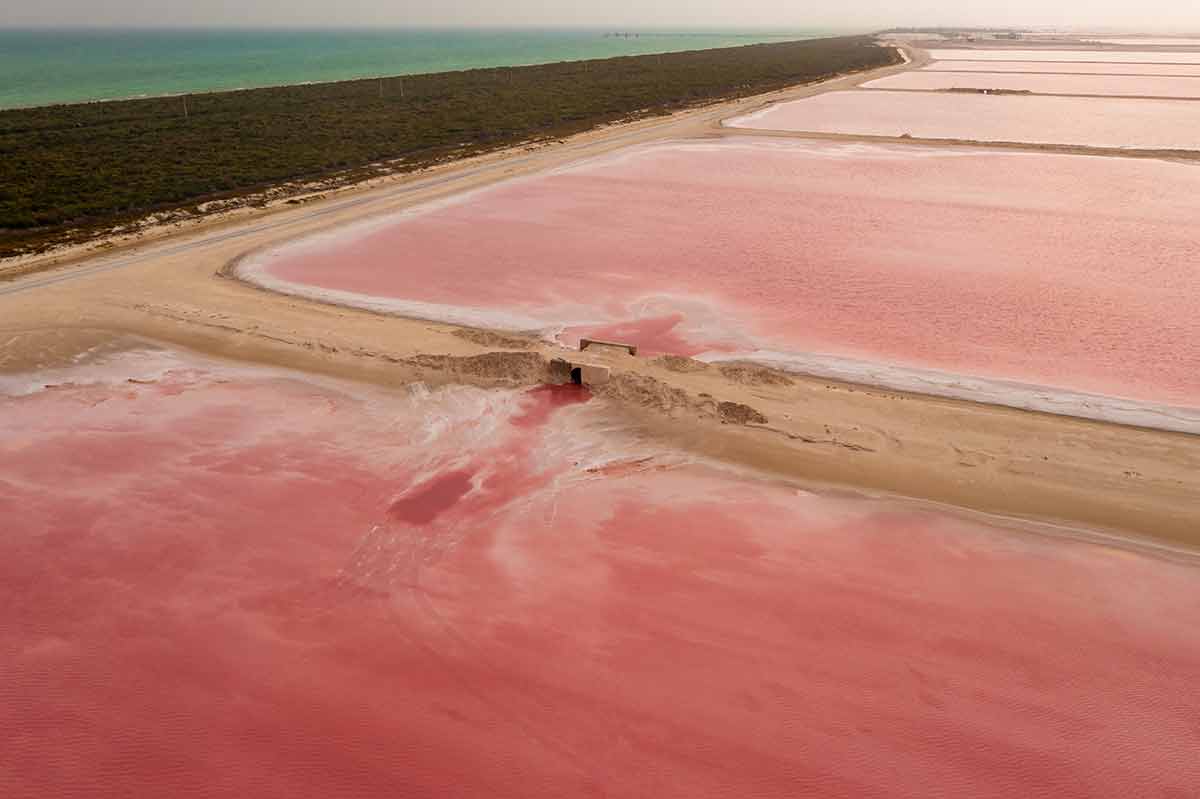 unique things to do in cancun Aerial view of the pink salt lakes separated by a sand spit from the Gulf of Mexico on the Yucatan in Mexico.