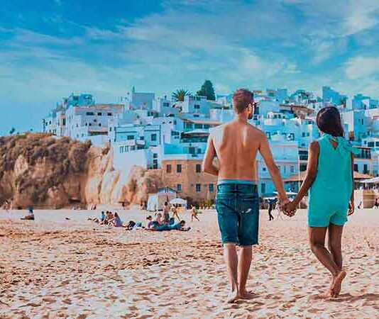 Happy Young Couple Walking At The Beach Of Albufeira Algarve