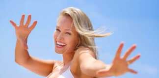 Pretty blond wearing white bikini top smiling on the beach