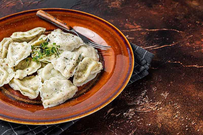warsaw things to do in winter Polish Pierogi Dumplings with potato on a plate with herbs and butter.