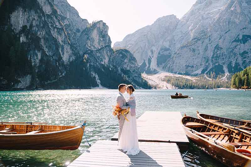 The Bride And Groom Walk Along A Wooden Boat Dock