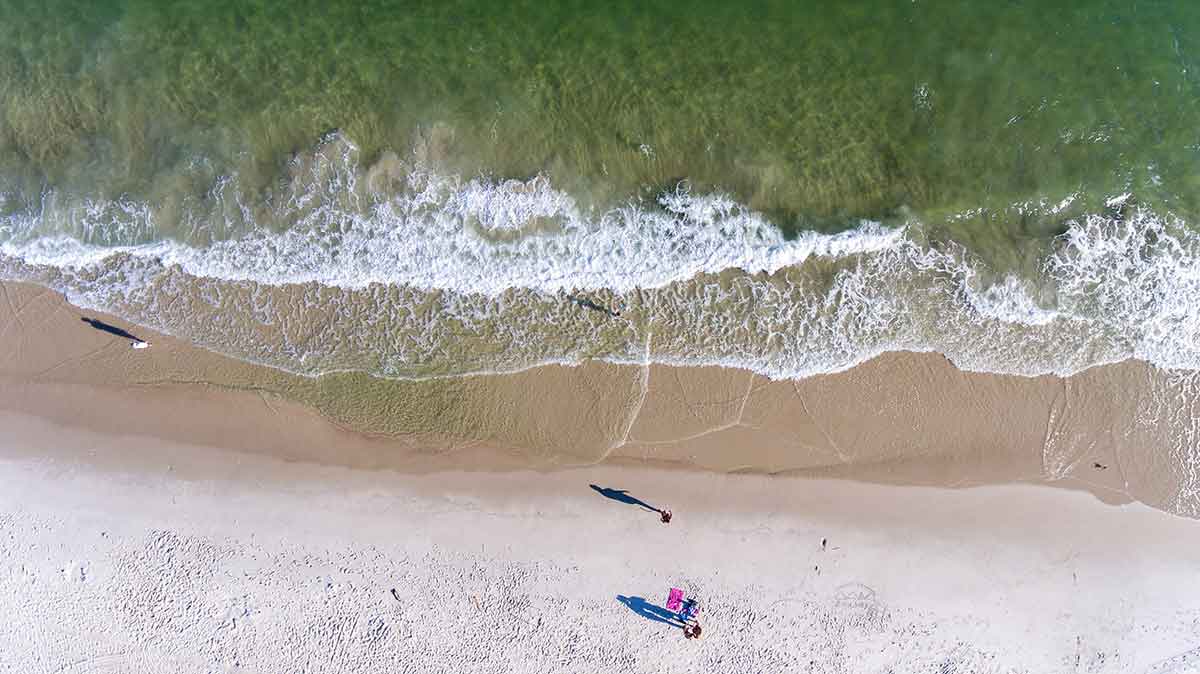 aerial view of sand and waves and people on a beach