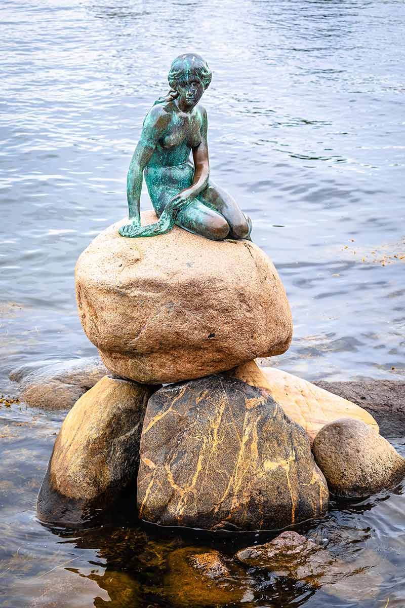 Little Mermaid Statue Displayed On A Rock By The Waterside
