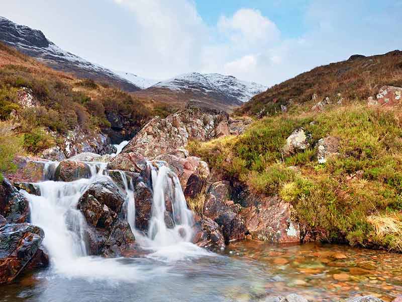 what is the best time of year to visit scotland Rapids in small waterfall on stream and dry grass and heather bushes on banks.