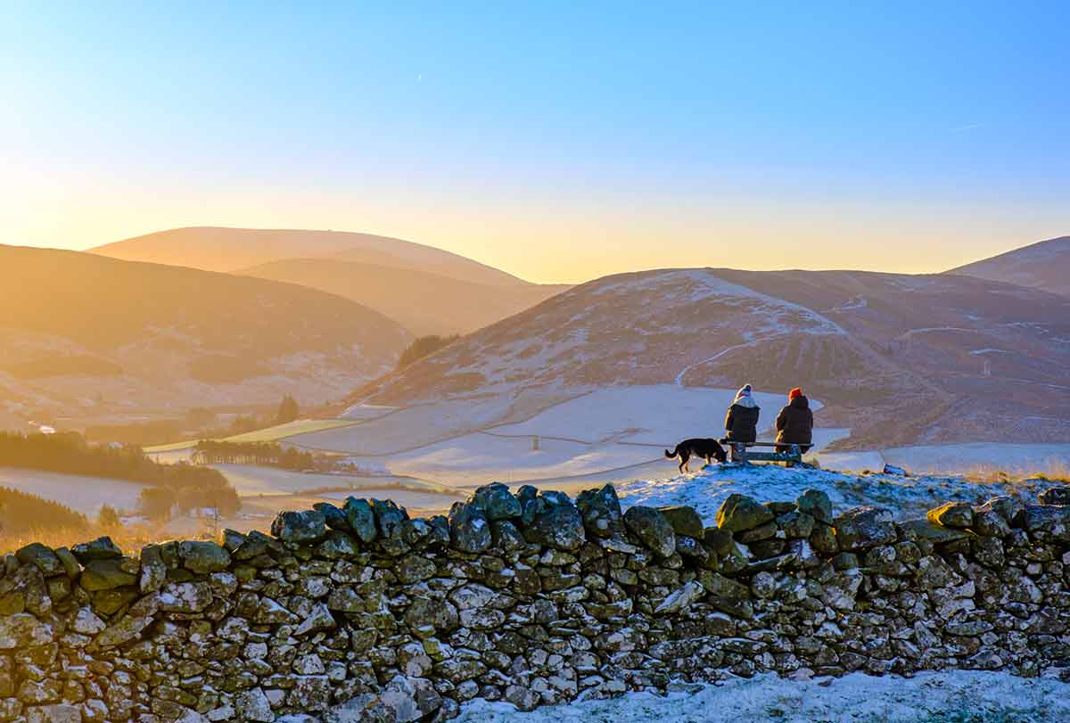 when is the best time of year to visit scotland two friends sitting on a bench on a frosty morning with dog
