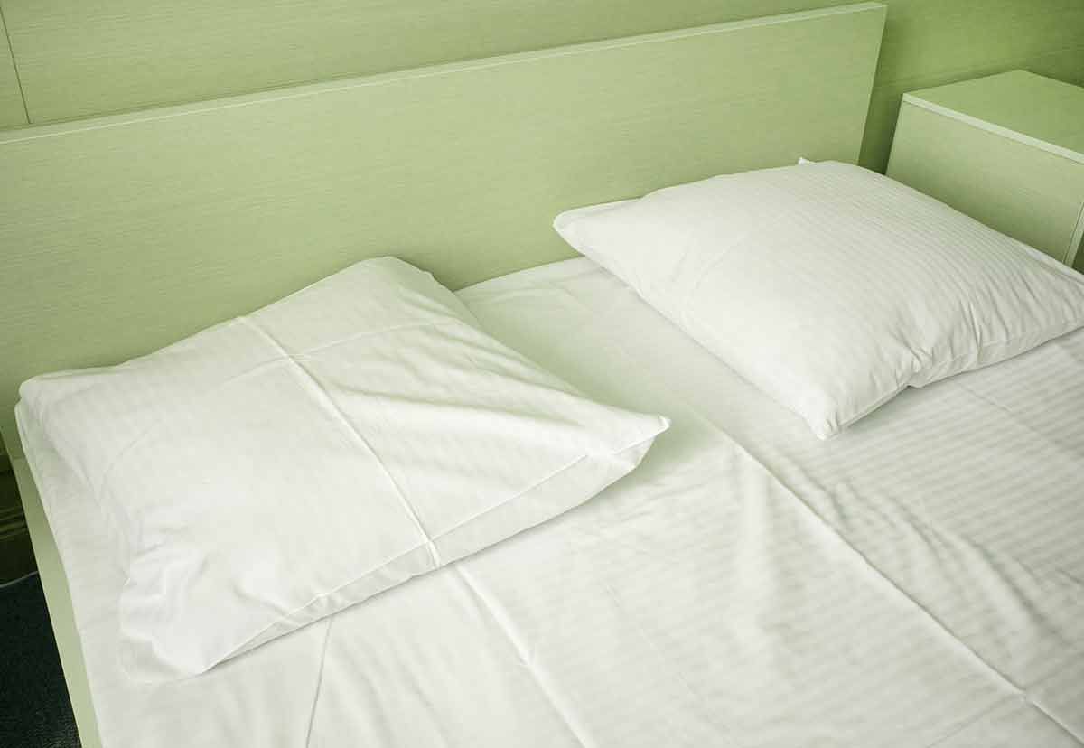 Light green tinting, close-up of white sheets and pillow in a hotel room, modern interior.