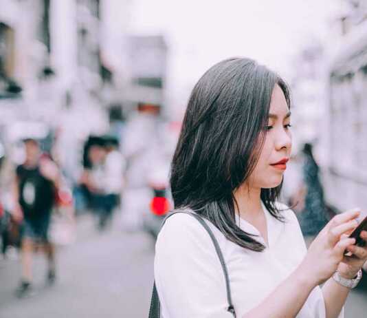Side View Of A Young Woman using her mobile in Khao San.