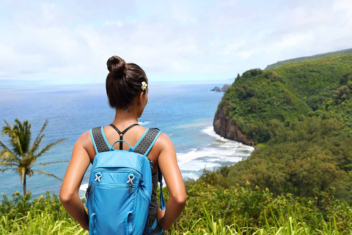 girl hiking in Pololu valley enjoying lookout view of mountains