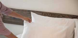 Cropped image of a female chambermaid making bed in hotel room.