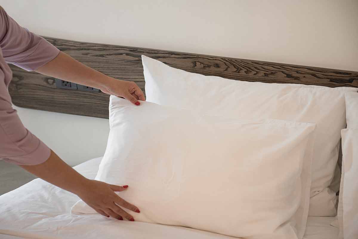 Cropped image of a female chambermaid making bed in hotel room.