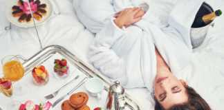 where to stay in los angeles as a tourist an attractive young woman in a bathrobe enjoying a luxurious breakfast in her room.
