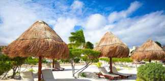 where to stay in tulum beach chaise lounges under an umbrella on sandy beach