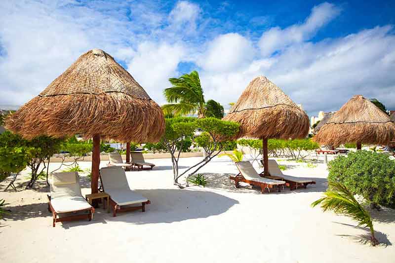 where to stay in tulum beach chaise lounges under an umbrella on sandy beach